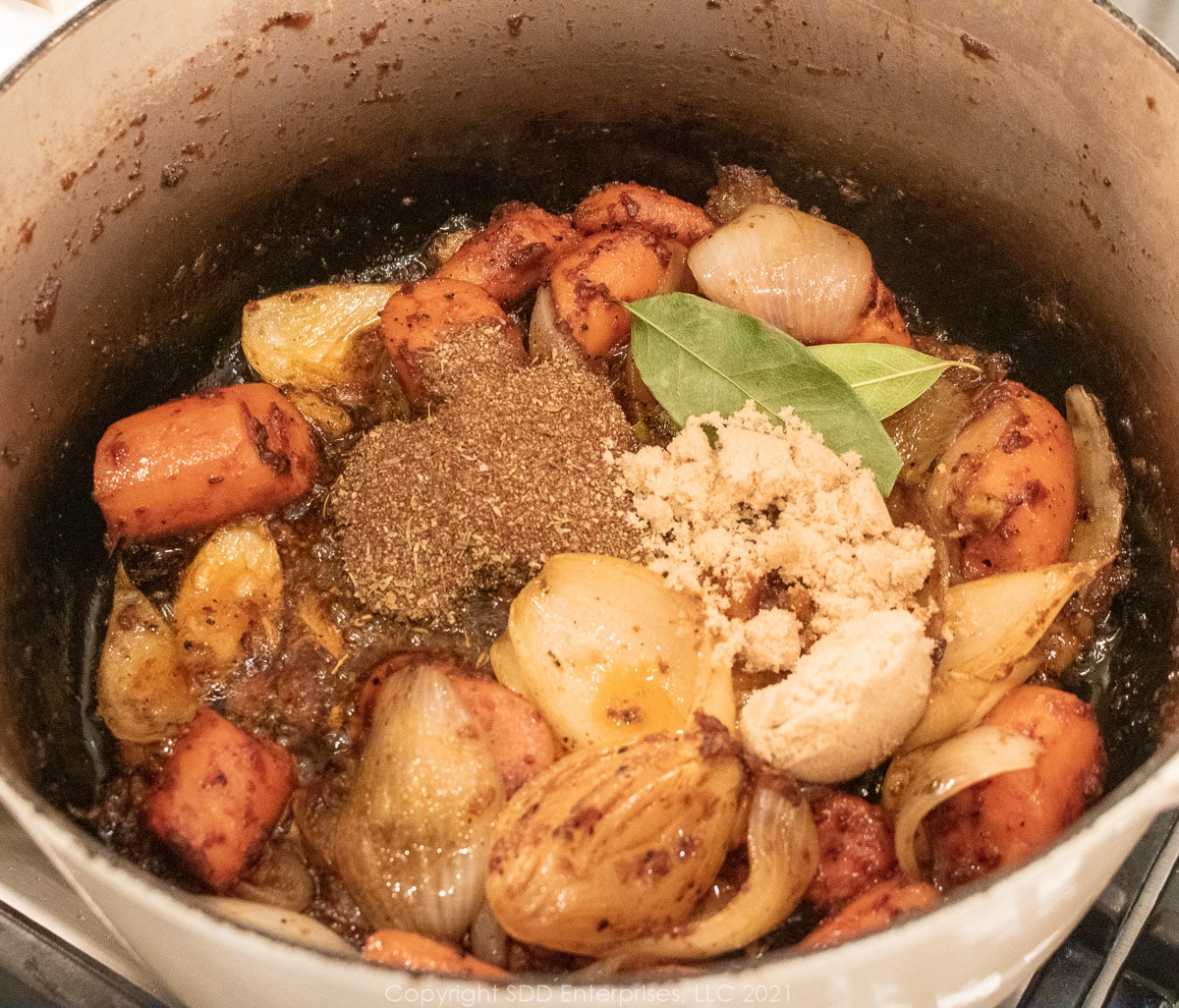 seasonings added to a Dutch oven with onions and carrots