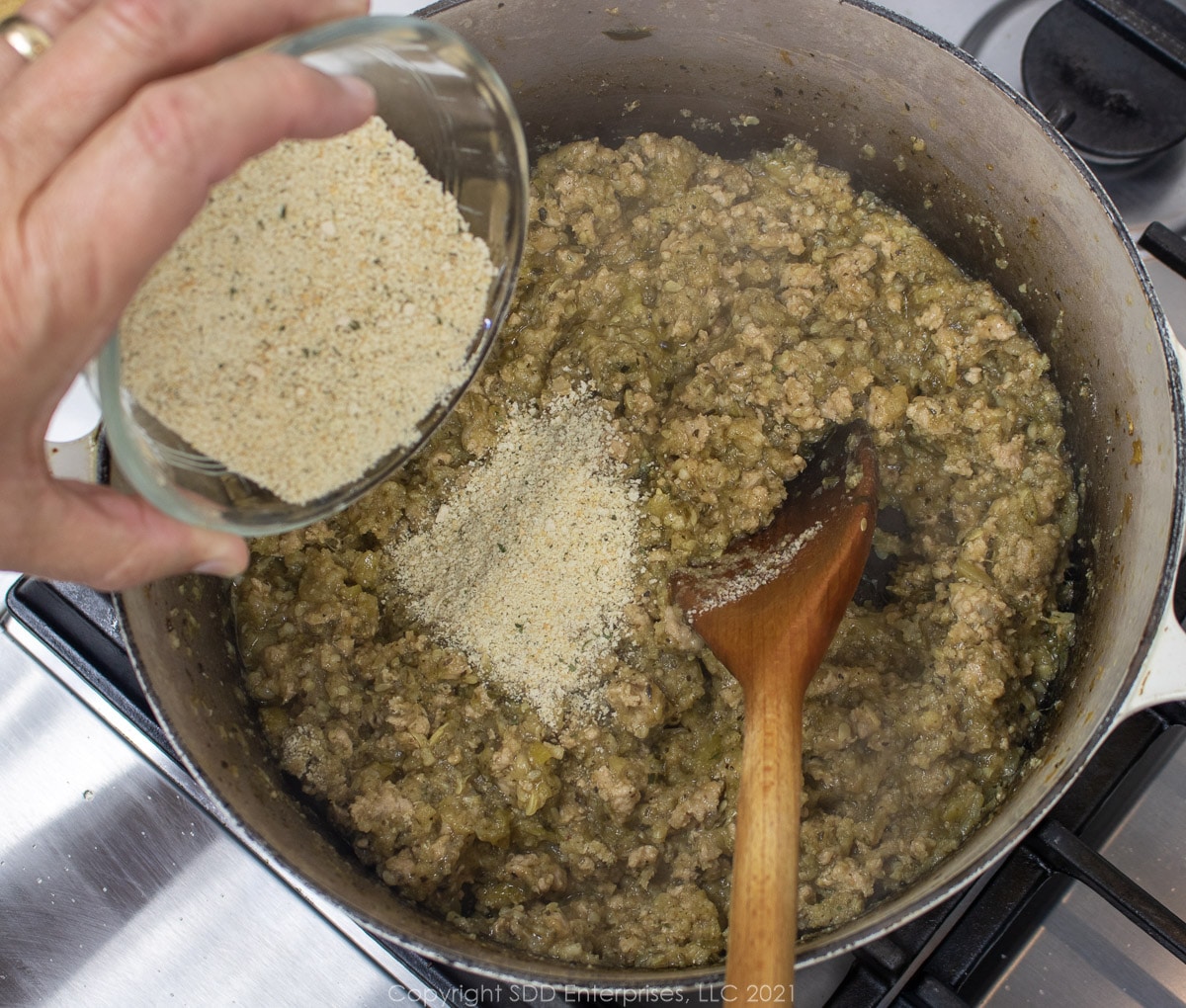 readcrumbs added to a Dutch oven with simmering pork and vegetables