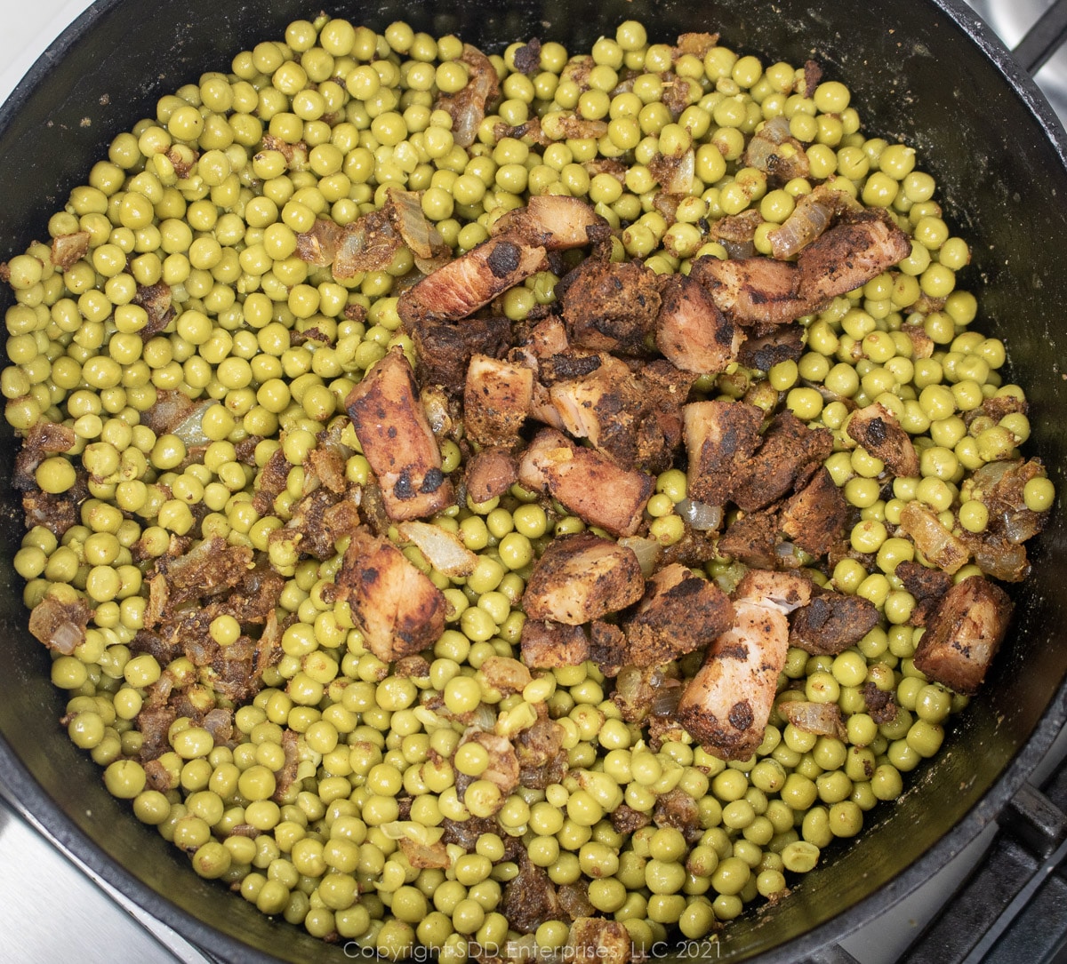 sweet peas and seasoning meat added to vegetables and roux in a Dutch oven