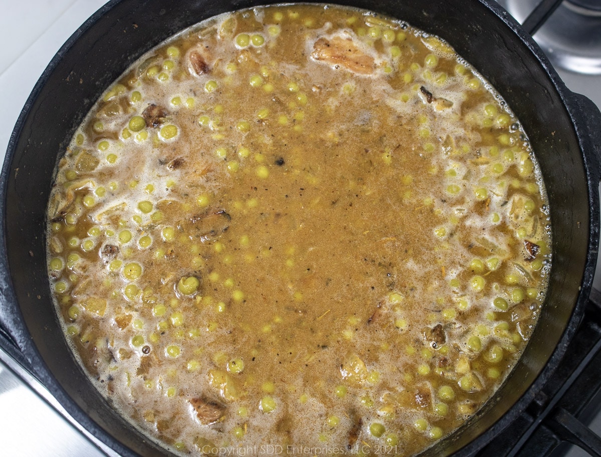 seasoned sweet peas simmering in stock in a Dutch oven