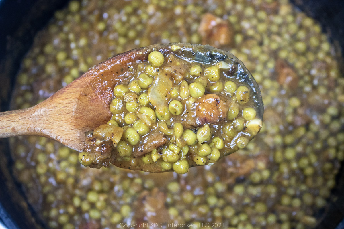 peas in a roux in a wooden spoon over a Dutch oven