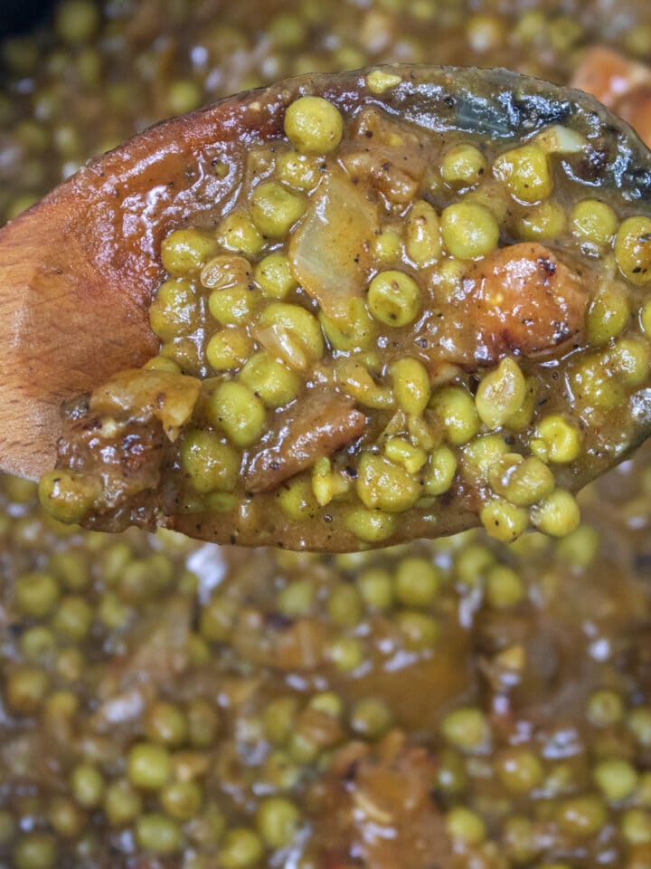 peas in a roux in a wooden spoon over a Dutch oven