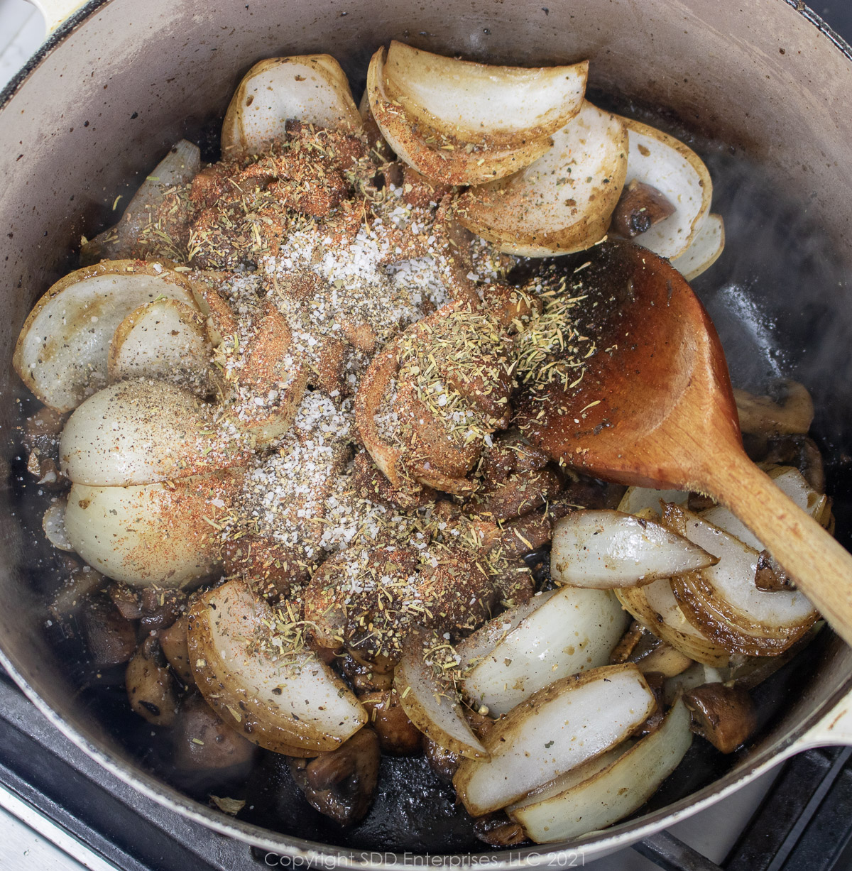 garlic and herbs added to onions and mushrooms in a Dutch oven