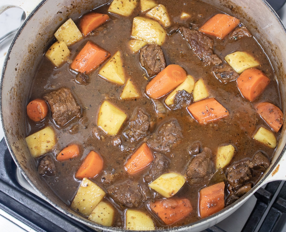 potatoes added to carrots and beef in a Dutch oven