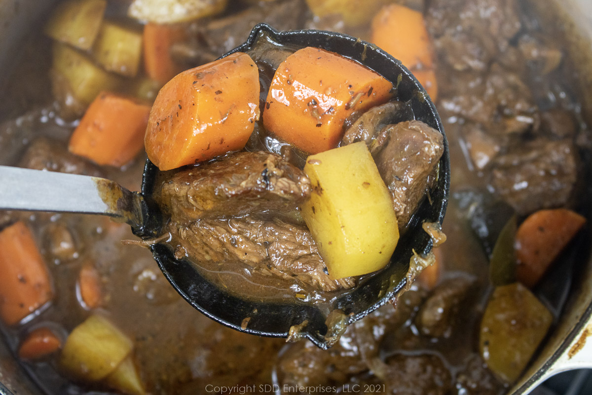 beef stew with carrots and potatoes in a ladle