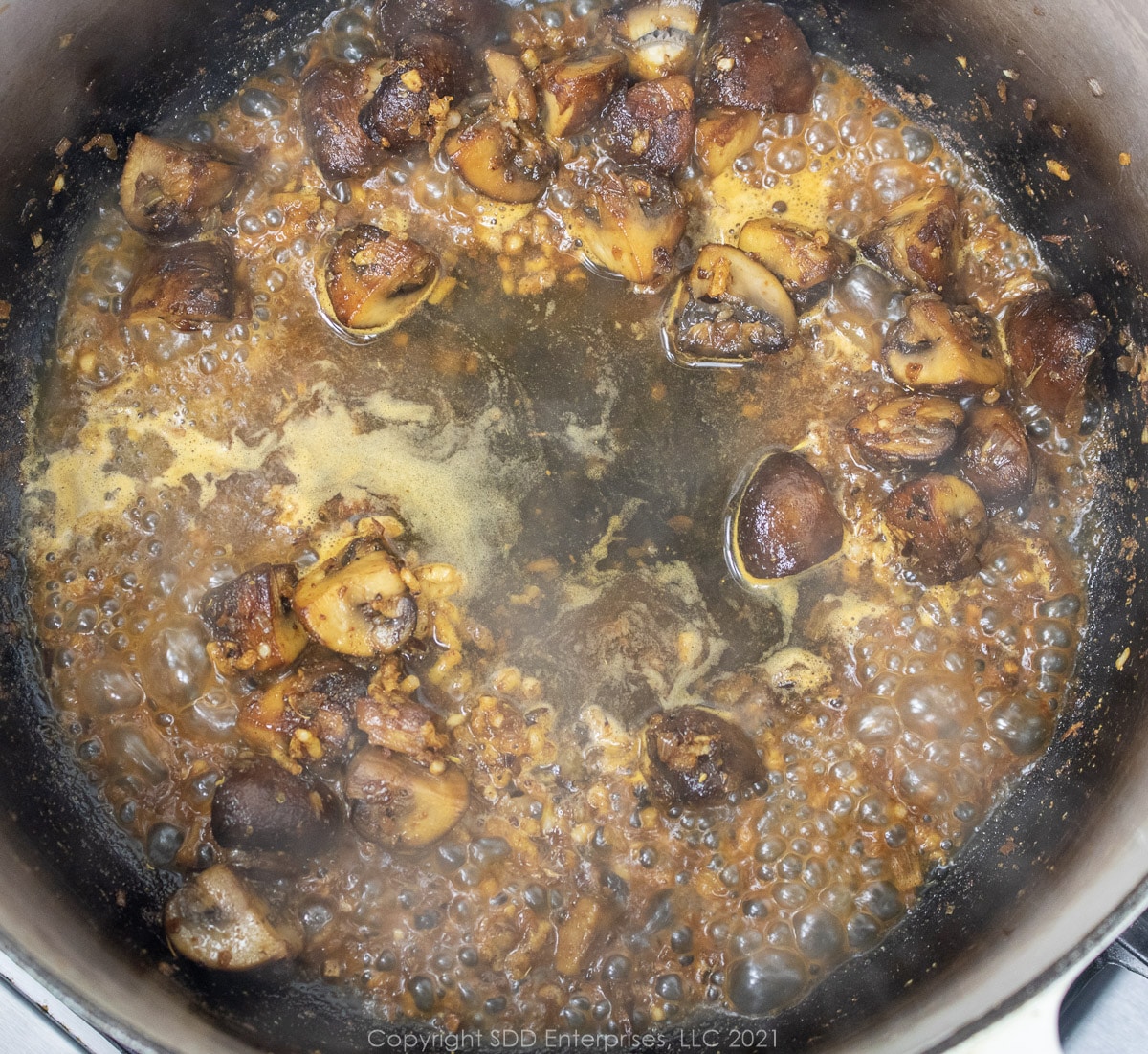 wine added to shallots and mushrooms in a cast iron skillet