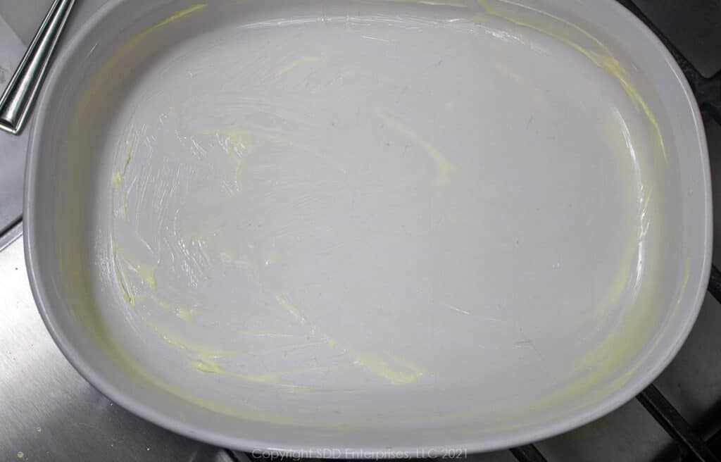 white baking dish prepared with softened butter