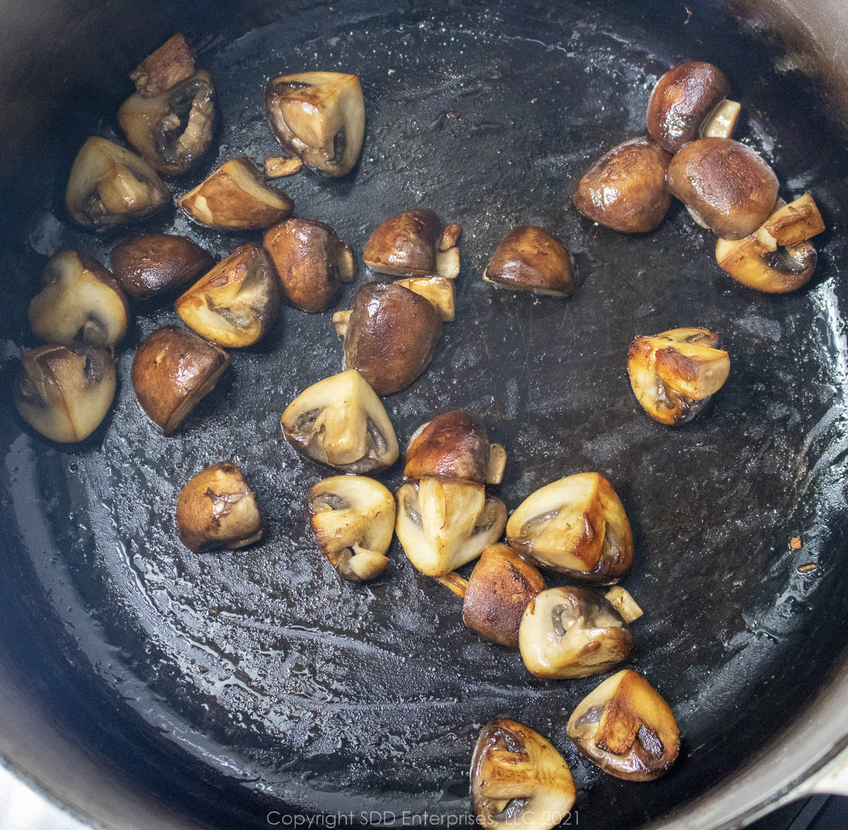 mushrooms browning in a cast iron skillet