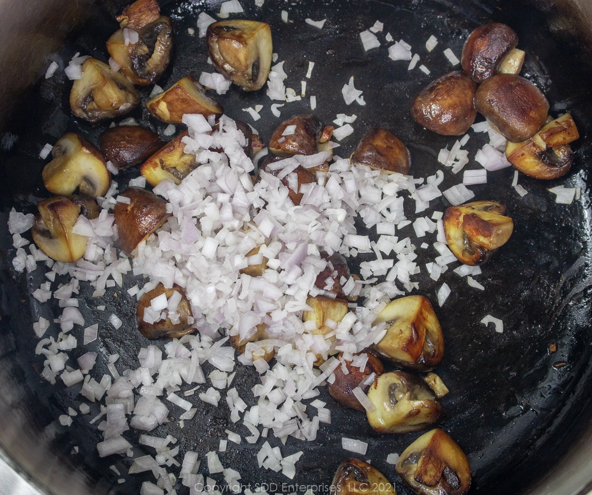 shallots and mushrooms browning in a cast iron skillet