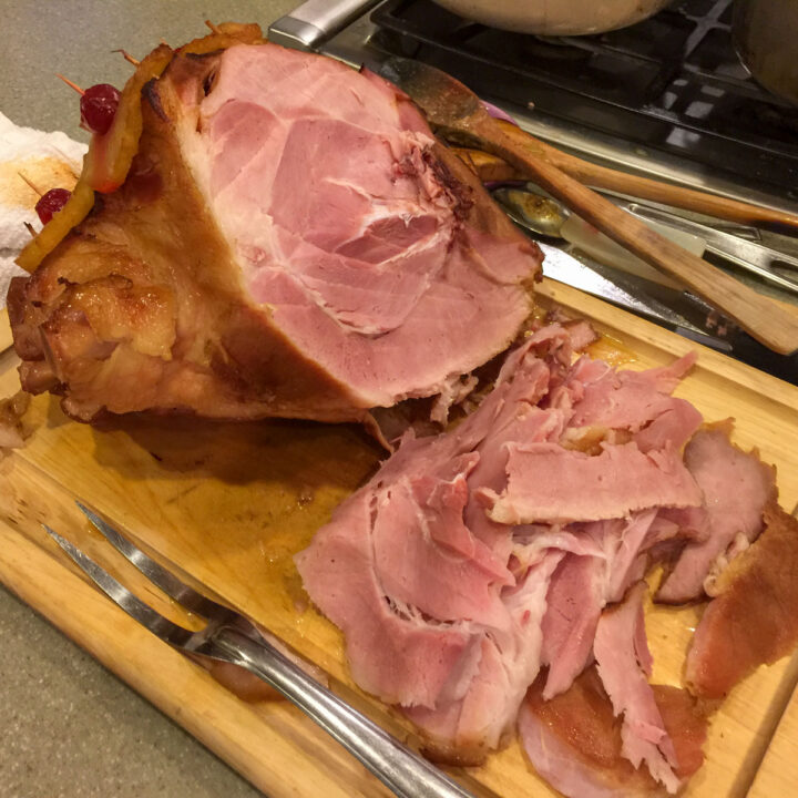 baked ham on a cutting board with a fork