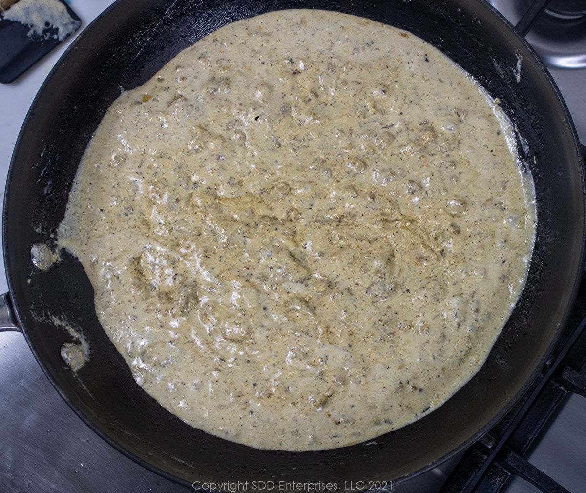 cream thickening with artichoke hands in a sauté pan