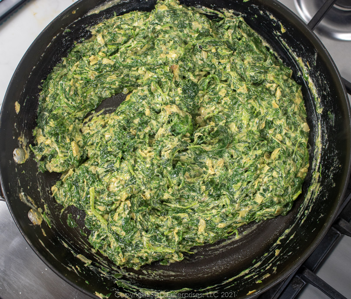 creamed spinach with artichoke in a sauté pan