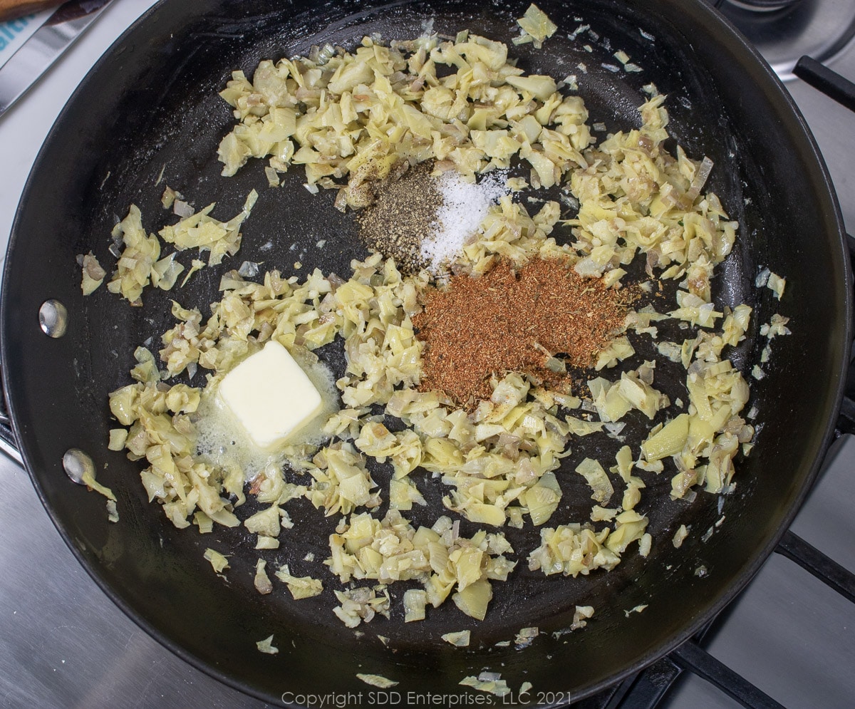 seasonings added to artichoke heats and shallots in a sauté pan