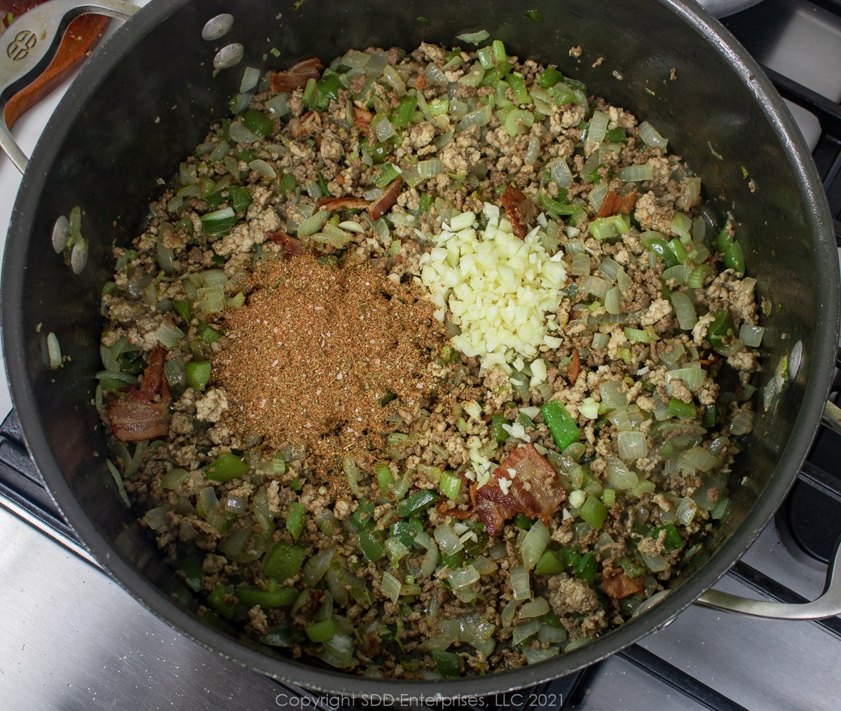 garlic and herbs added to browning meat and vegetables in a Dutch oven