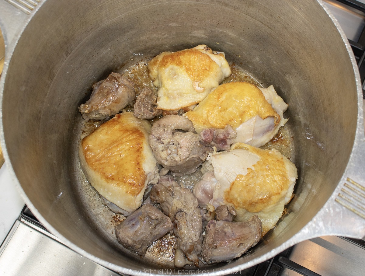 browning chicken thighs and turkey necks in a stock pot