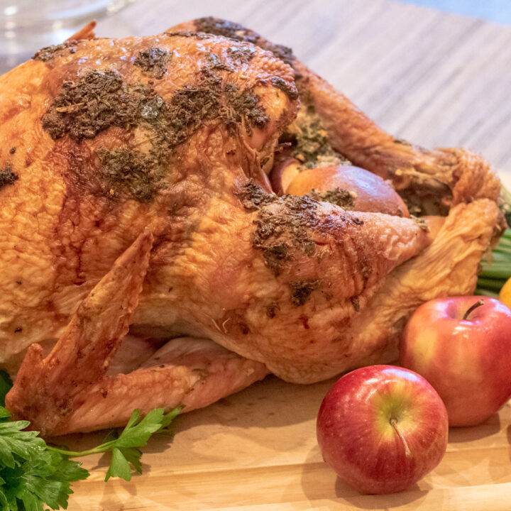 herb roasted turkey on a cutting board with apple and parsley garnish