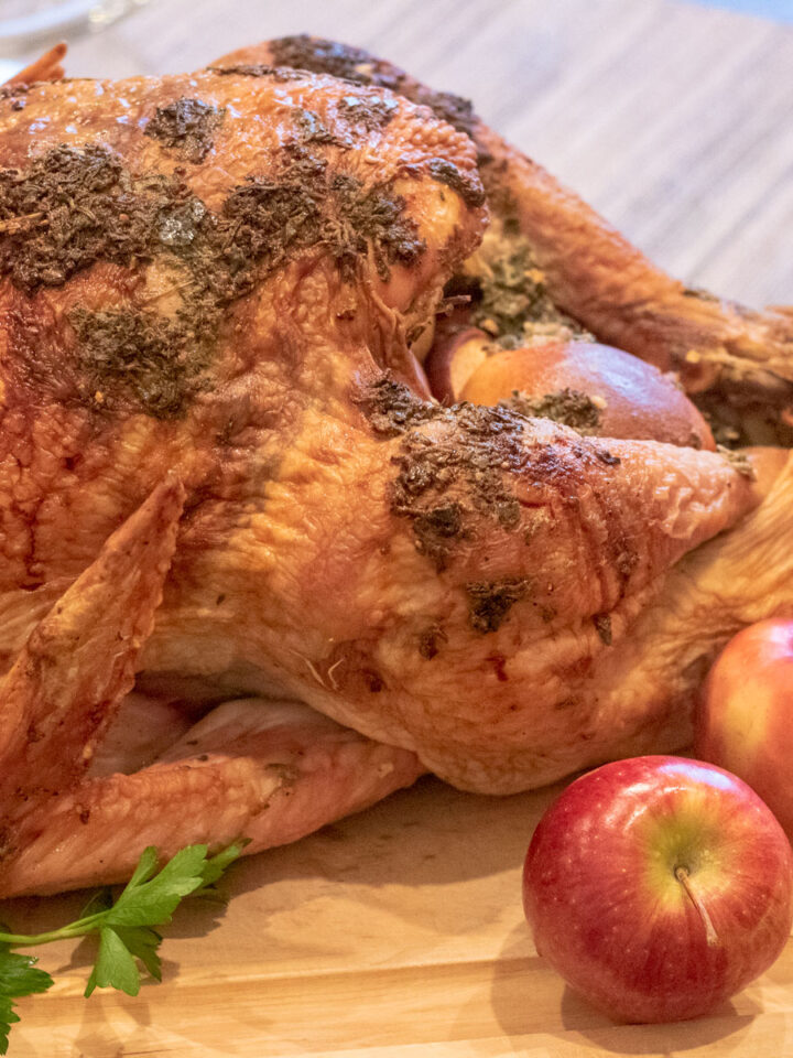 herb roasted turkey on a cutting board with apple and parsley garnish