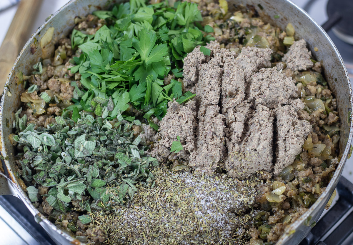 giblets, fresh parsley, fresh sage, herbs and spices added to browned sausage in a frying pan