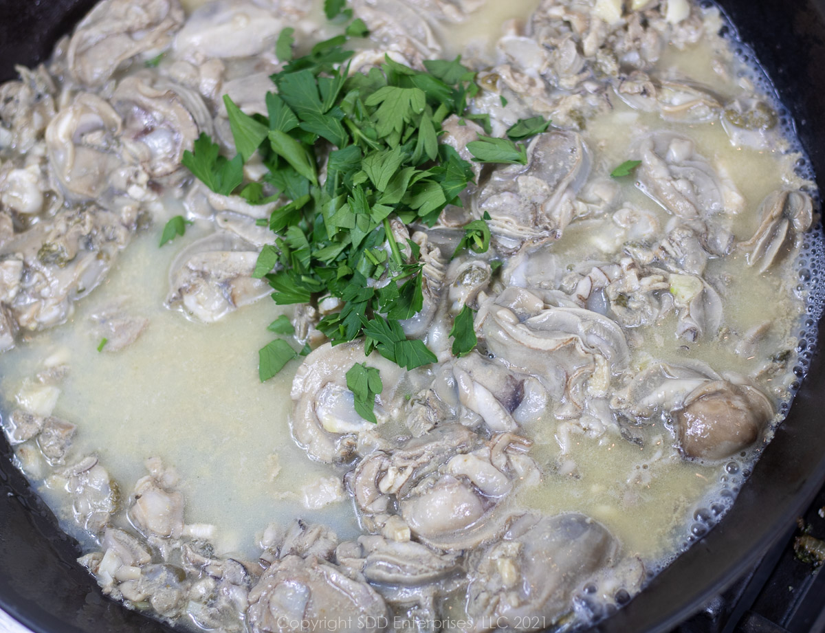 fresh oysters and fresh parsley added to butter and garlic in a sauté pan
