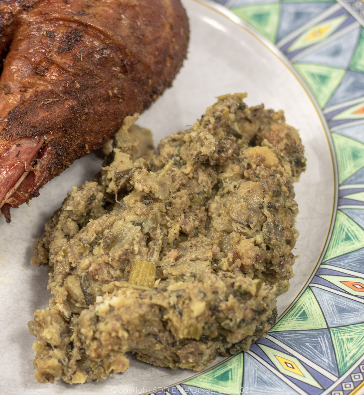 New Orleans oyster dressing on a white and green plate with a turkey leg