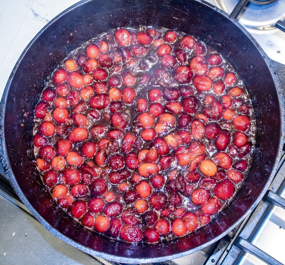 whole cranberries simmering in spices in a Dutch oven