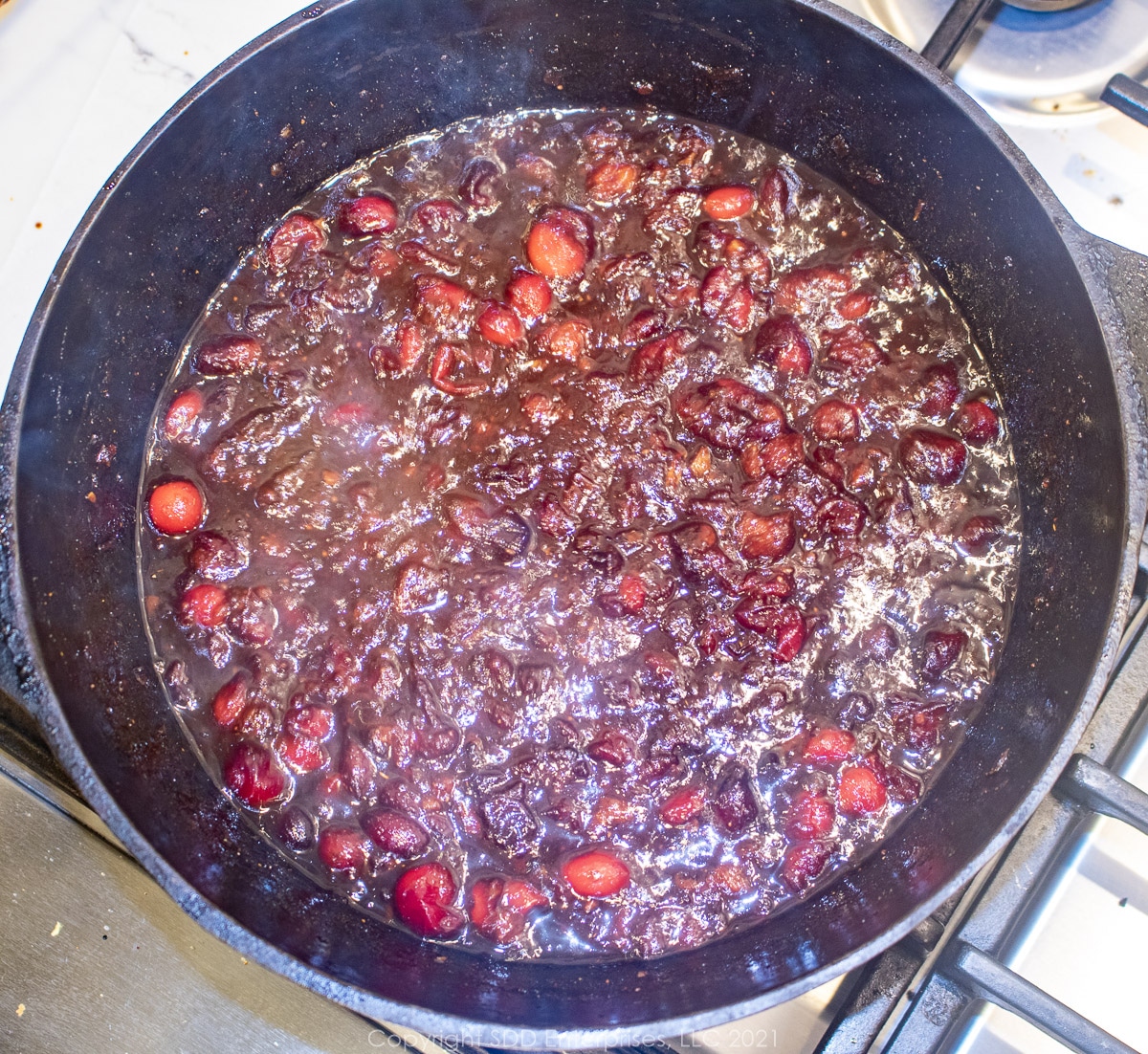 simmering whole cranberries break dow in spices in a Dutch oven