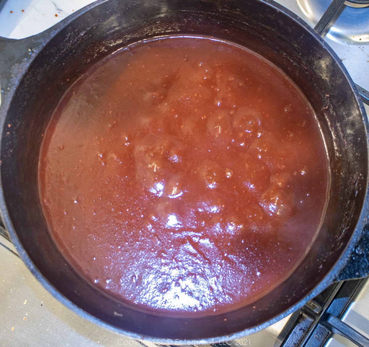 simmering cranberry bbq sauce in a Dutch oven