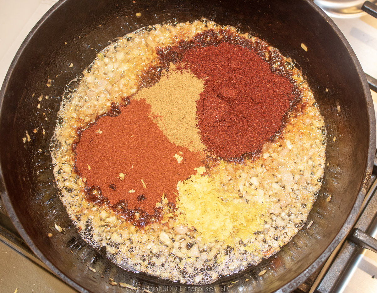 savory spices added to onions and garlic for bbq sauce in a Dutch oven