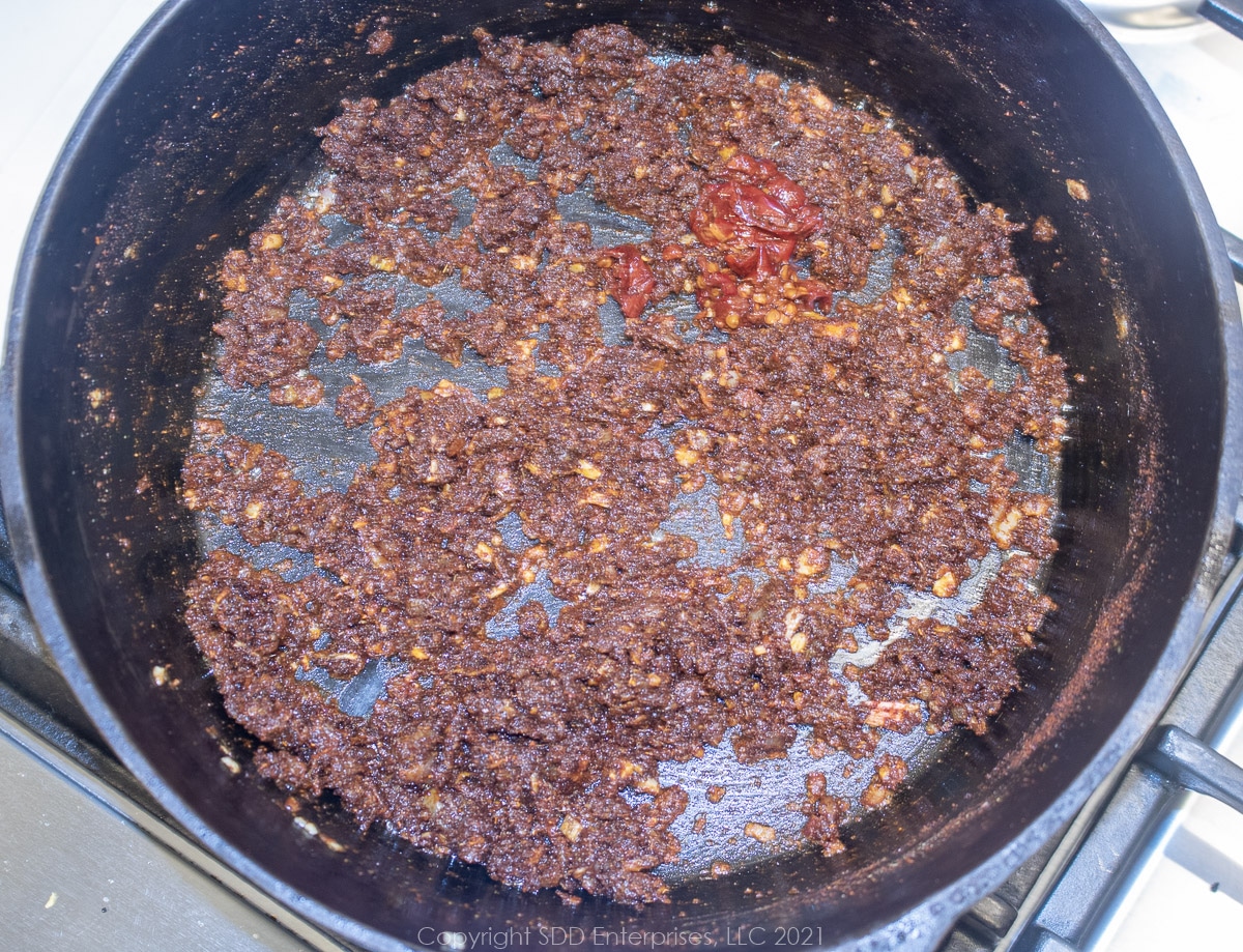 chipotle peppers added to spices and veggies in a Dutch oven
