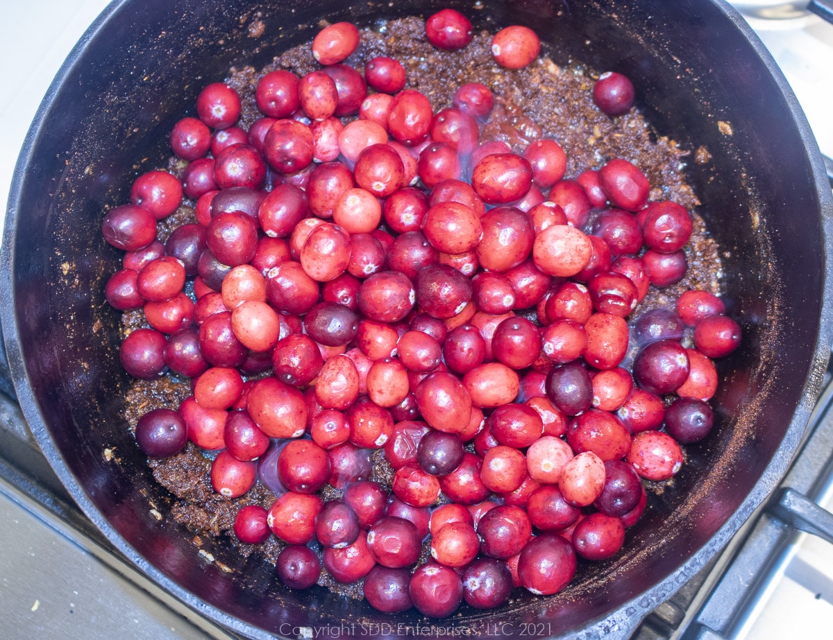 whole cranberries added to onions, peppers and spices in a Dutch oven