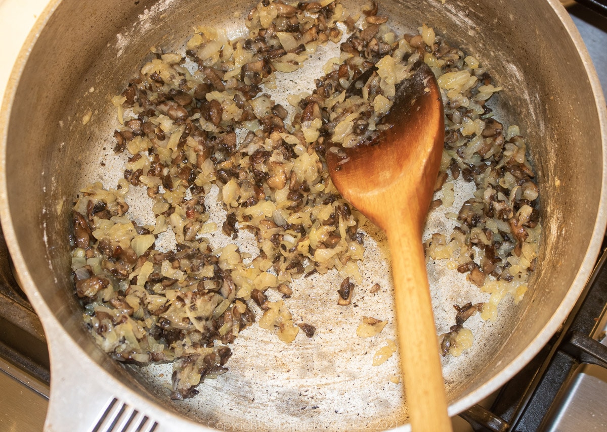 AP flour added to mushrooms and onions in a frying pan