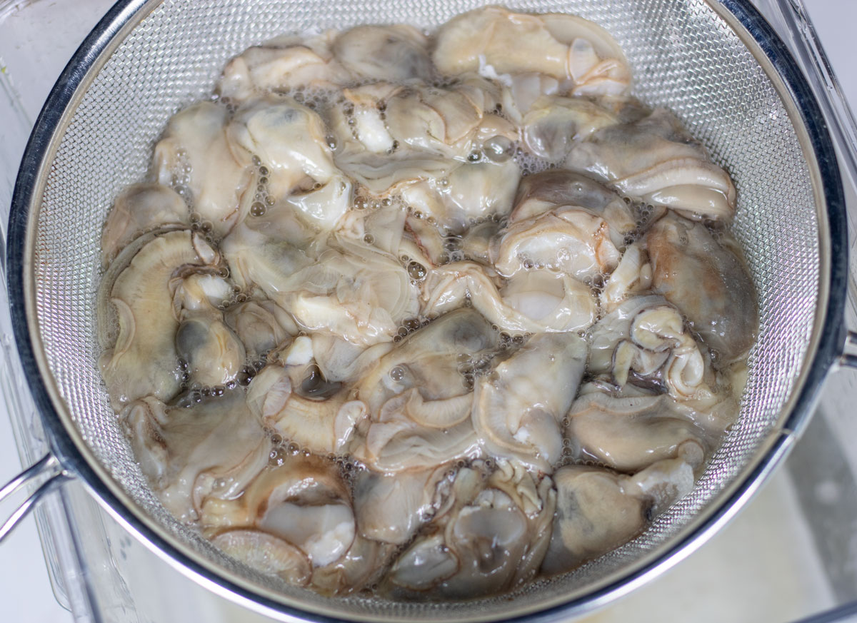 fresh oysters draining in a strainer