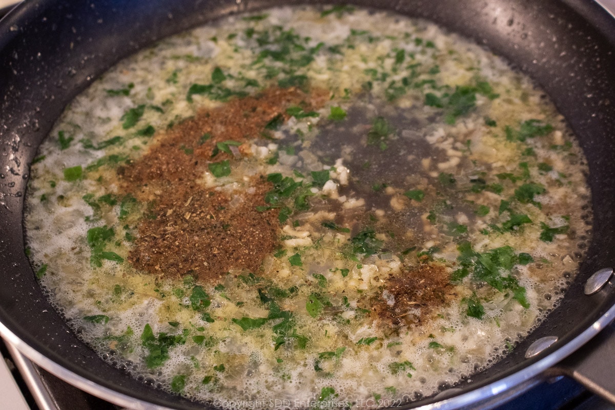 herbs and oyster juice added to the sautéing vegetables in a pan