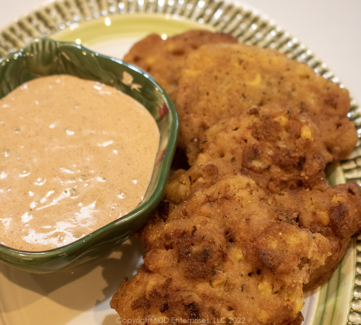 crawfish and corn fritters on a plate with dipping sauce