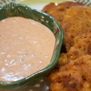 dipping sauce in a small green bowl with fritters on the side