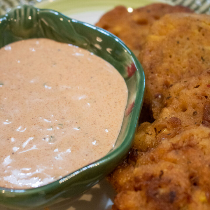 dipping sauce in a small green bowl with fritters on the side