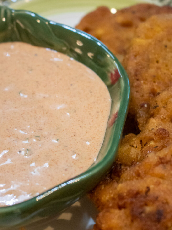 dipping sauce in a small green bowl with fritters on the side