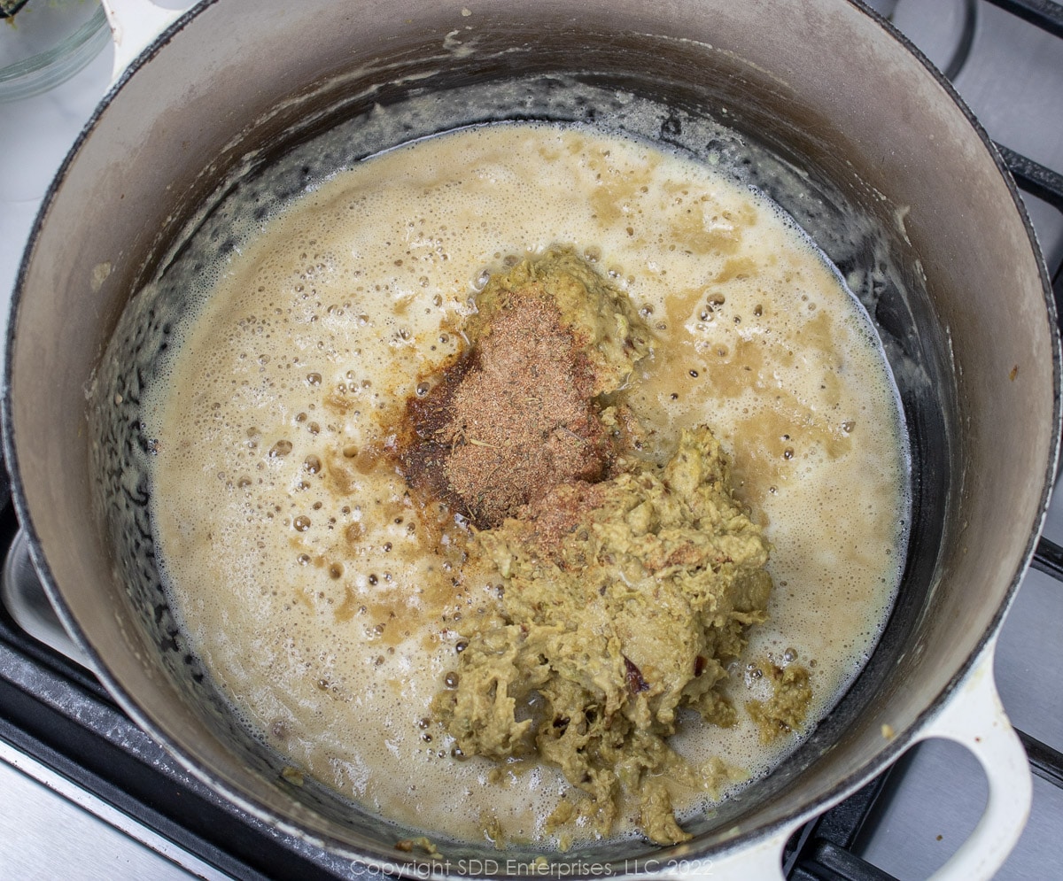 pureed vegetables and seasonings added to a roux in a Dutch oven