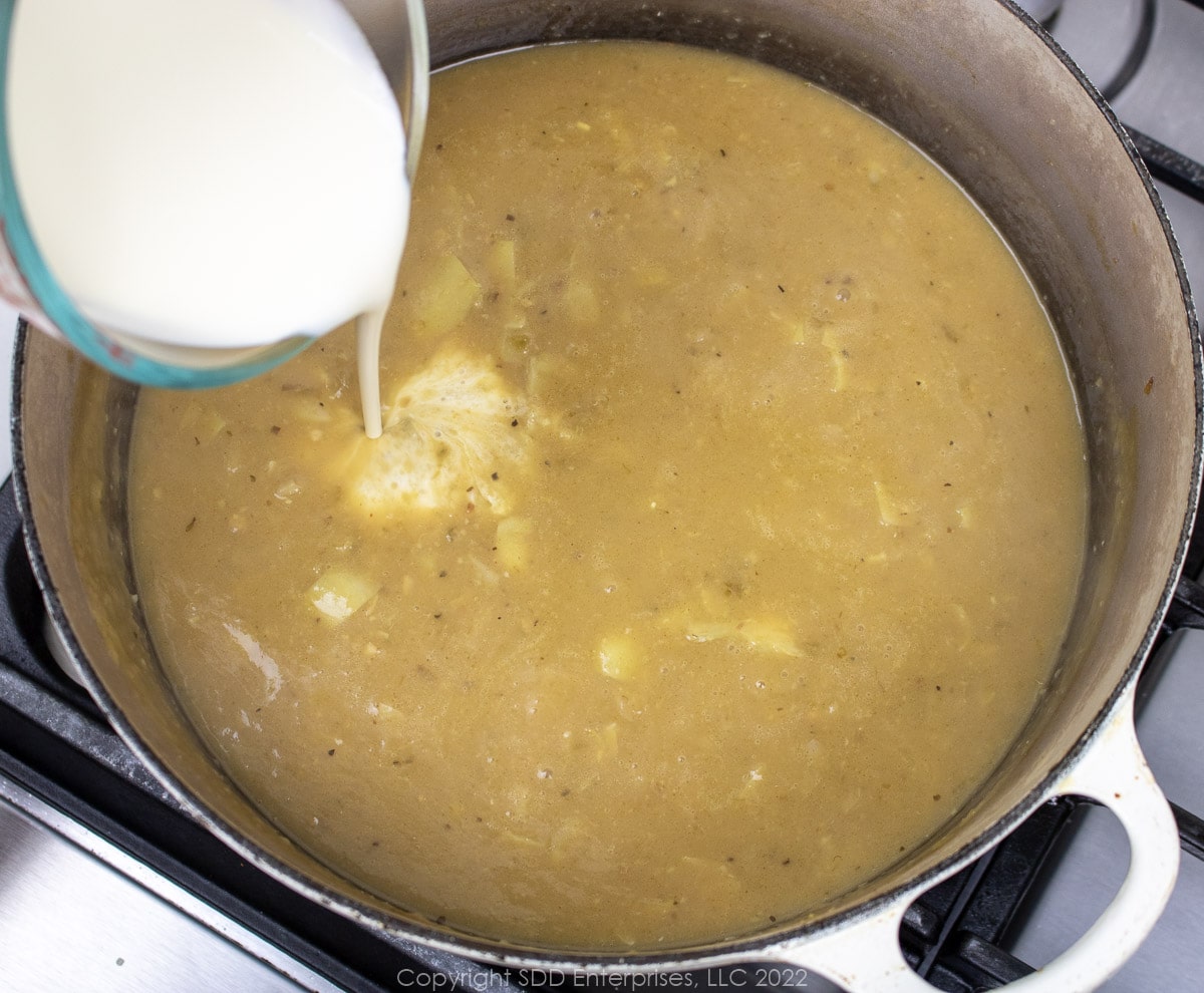 heavy cream eing added to simmering stock in a Dutch oven