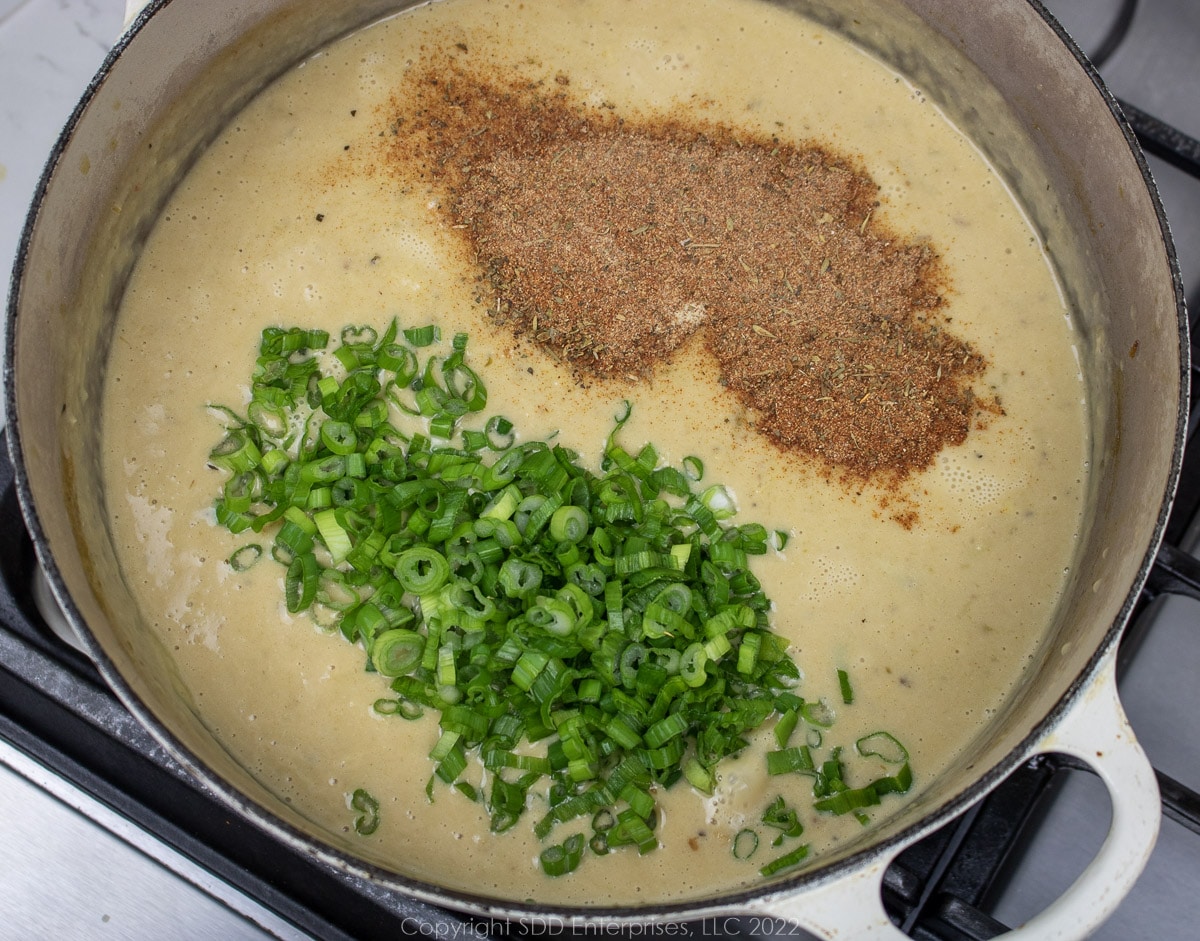 green onions and seasonings added to bisque in a Dutch oven