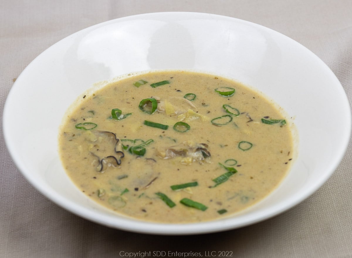 oyster artichoke bisque with garnish in a white bowl