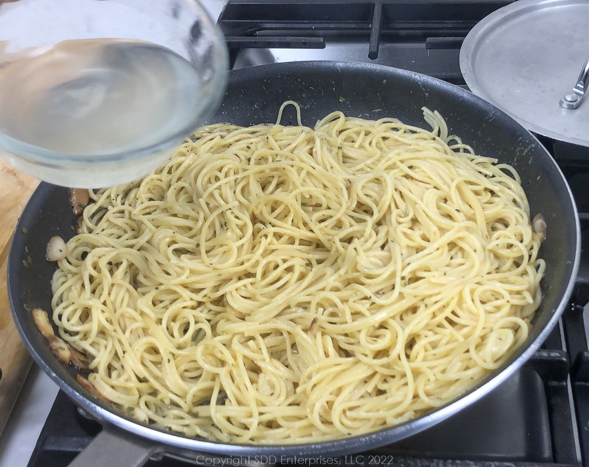 adding pasta water to spaghetti in a sauté pan