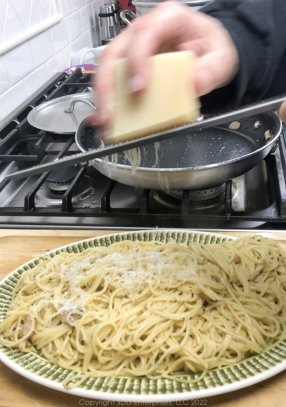 grating parmesan cheese over spaghetti