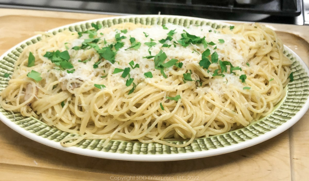 spaghetti bordelaise on a platter with parmesan and parsley garnish