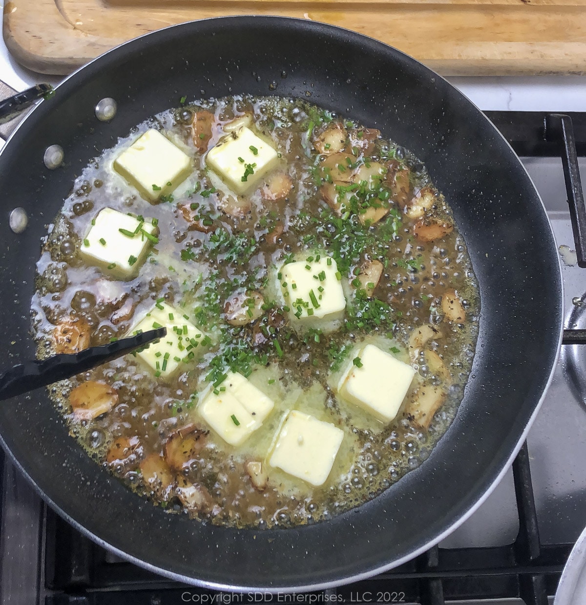 butter, chives and parsley added to garlic butter in a sauté pan