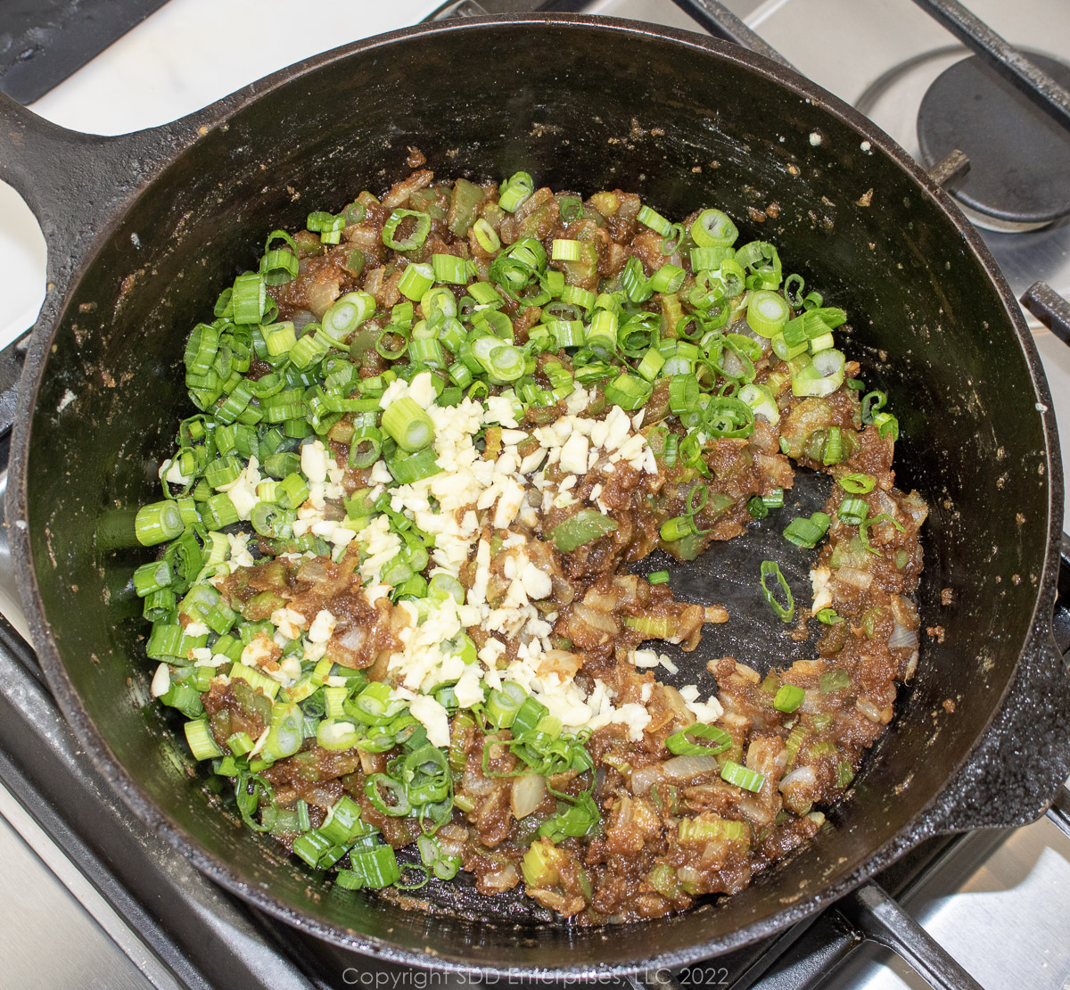chopped garlic and green onions added to a roux in a dutch oven
