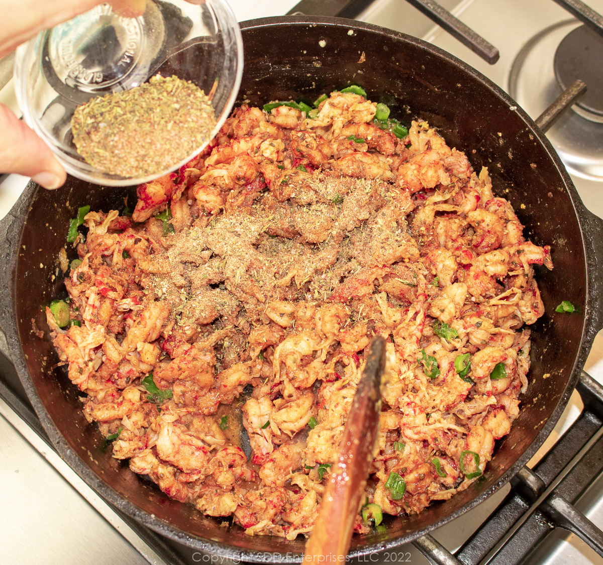 herbs and spices added to crawfish tails in butter