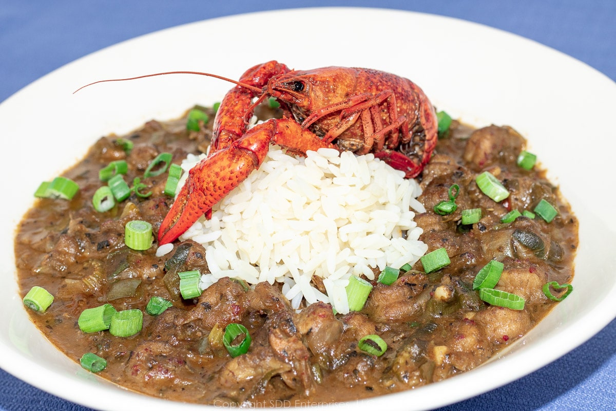 crawfish etouffee in a white bowl with rice and a crawfish garnish