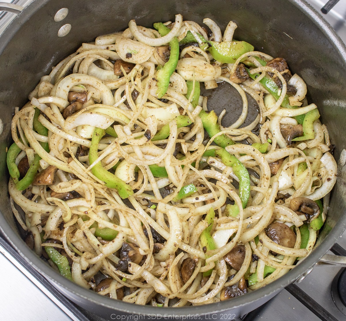 onions and bell peppers browning with mushrooms in a Dutch oven