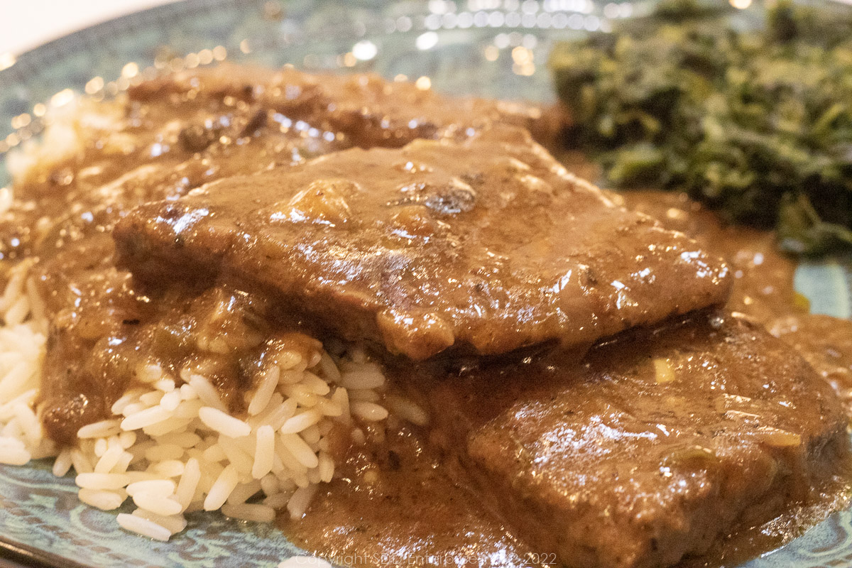 smothered round steak on white rice with spinach